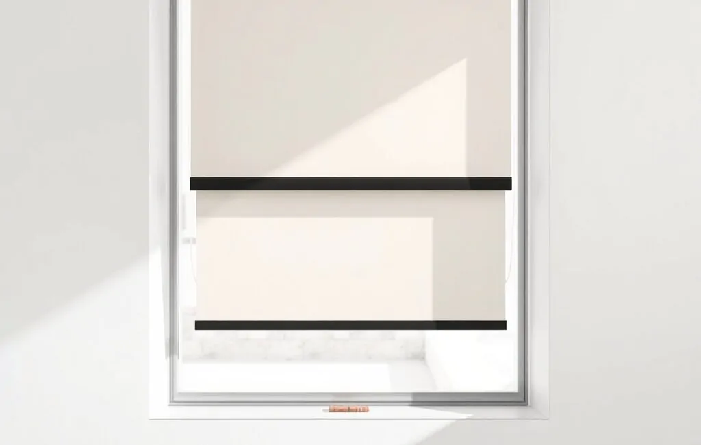 Persiana reparada en color marfil con cassette negro, iluminada por luz mediterránea, sugiere ajustes recientes. Cuales son los mejores servicios de reparacion de persianas en Barcelona.