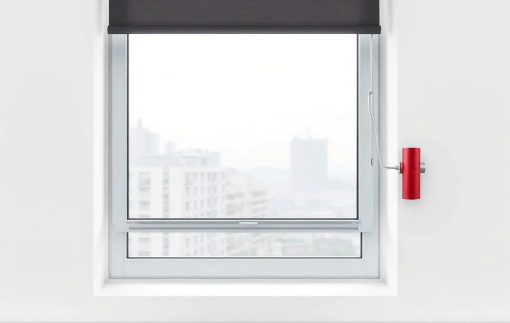 Persiana geométrica gris con motor rojo en ventana, fondo de bloques grises; opciones efectivas de motorización para locales comerciales.